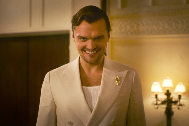 Ray Nicholson as Paul Hudson in Smile 2. He is wearing a white suit and smiling in a sinister fashion at the camera