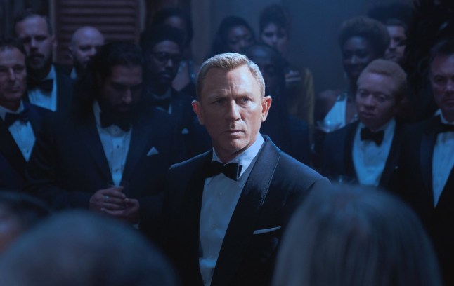 Daniel Craig as James Bond surrounded by men wearing tuxedos