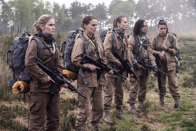Jennifer Jason Leigh, Natalie Portman, Tuva Novotny, Tessa Thompson and Gina Rodriguez stand in a line outside, holding rifles and dressed in matching brown combat outfits, looking at something in a scene from Annihilation