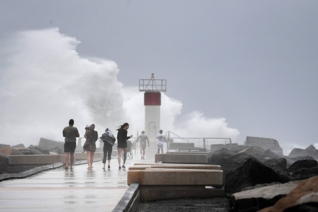 epa11936616 Onlookers observe the weather in the Seaway on the Gold Coast, Australia, 03 March 2025. The Queensland Government issued a warning on 03 March for the expected landfall of Tropical Cyclone Alfred. EPA/JONO SEARLE AUSTRALIA AND NEW ZEALAND OUT