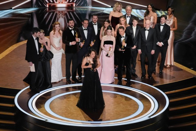 Samantha Quan, front center, accepts the award for best picture for "Anora" during the Oscars on Sunday, March 2, 2025, at the Dolby Theatre in Los Angeles. Alex Coco, from rear left, Darya Ekamasova, Lindsey Normington, Vache Tovmasyan, Karren Karagulian, Vincent Radwinsky, Luna Sof??a Miranda, Mikey Madison, Sean Baker, Mark Eydelshteyn, Yura Borisov, Meg Ryan, and Billy Crystal look on from back. (AP Photo/Chris Pizzello)