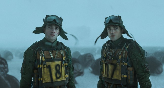 Robert Pattinson as Mickey 18 and Robert Pattinson as Mickey 17, standing outside in the ice in bomb vests.