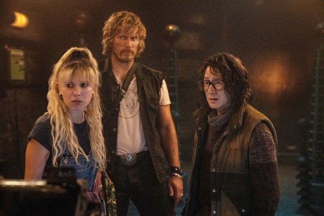 (L to R) Michelle (Millie Bobby Brown) , Keats (Chris Pratt) and Dr. Amherst (Ke Huy Quan) stad together and look worried in a scene from The Electric State