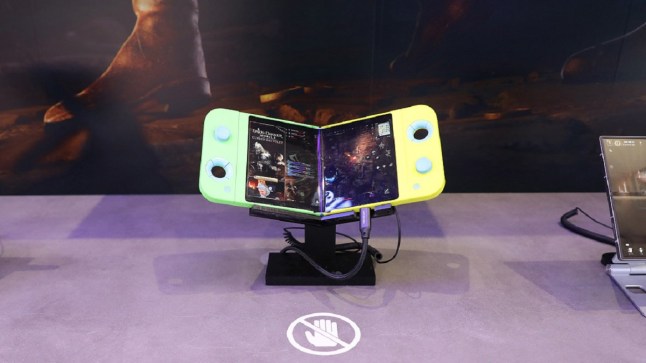 Samsung handheld gaming console that can fold in half resting on a small stand