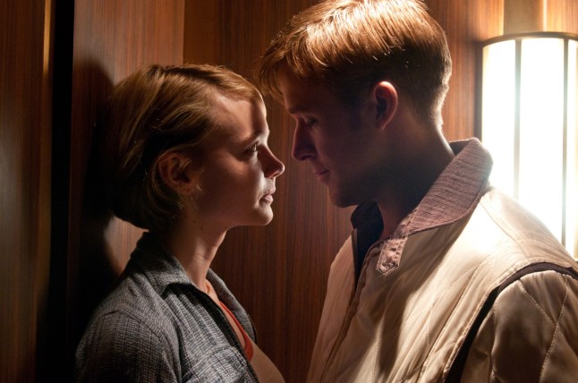 Carey Mulligan as Irene and Ryan Gosling as the Driver lean in for a kiss against a wall in the film Drive