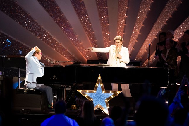 Brandi Carlile points to Elton John as he plays piano on stage at their joint show