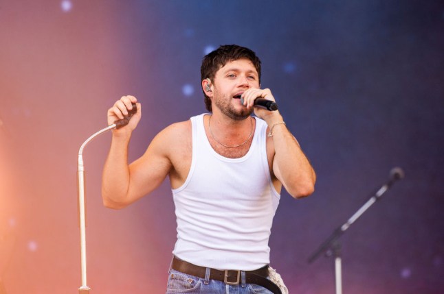 Niall Horan performs on stage in white vest top
