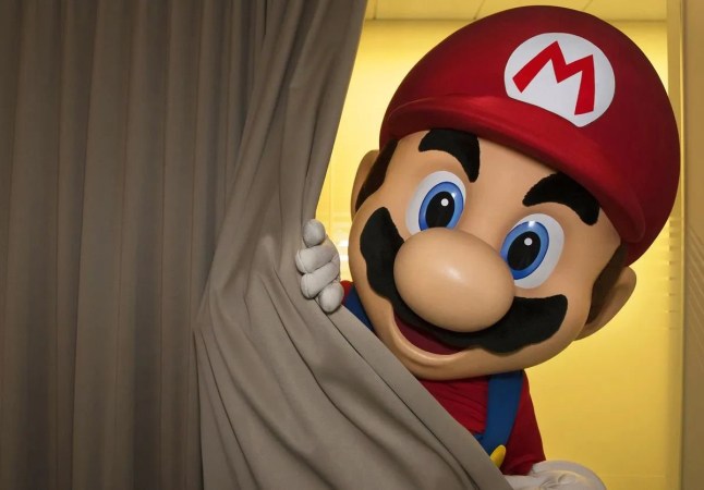 Man in a Super Mario costume peeking from behind a curtain