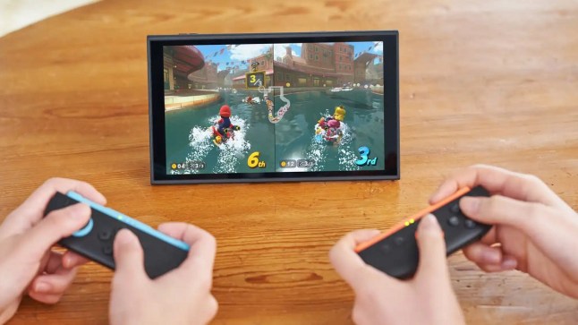 Two pairs of hands holding Joy-Con 2 controllers like playing Mario Kart World on the Nintendo Switch 2