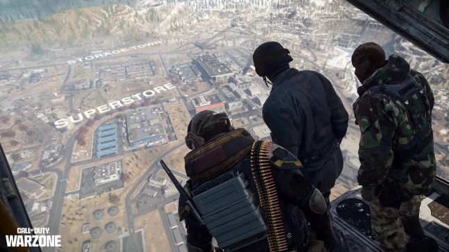 Three Call of Duty soldiers inside the back of a plane looking down to look at the map of Verdansk