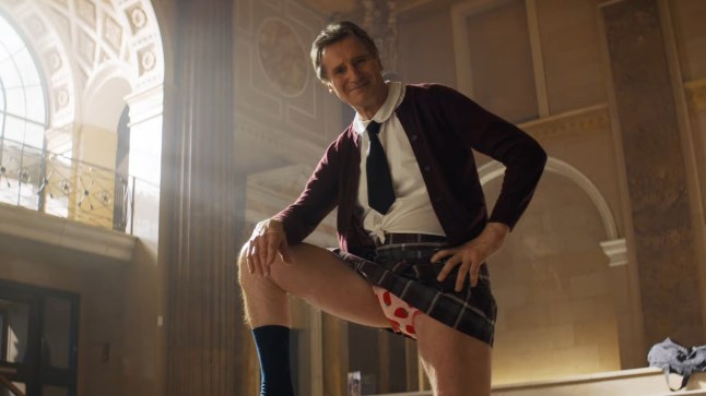 Liam Neeson in The Naked Gun, wearing schoolgirl uniform with his leg up, showing strawberry print pants.