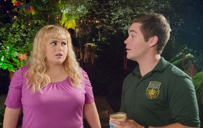 Rebel Wilson as Fat Amy in a pink top talks to Adam DeVine as Bumper Allen in a green group polo in Pitch Perfect 2
