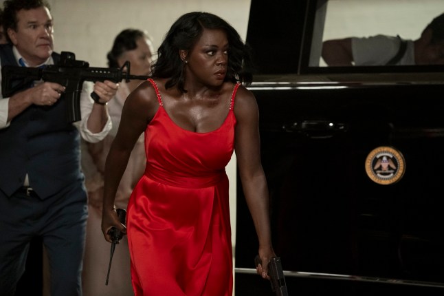 Viola Davis as President Danielle Sutton in a red satin evening gown with Douglas Hodge behind her holding a gun as Prime Minister Oliver Everett in G20