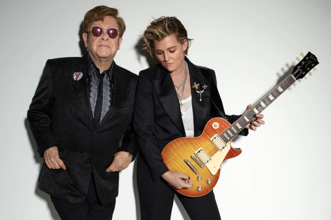 Sir Elton John poses with Brandi Carlile (R) who holds guitar