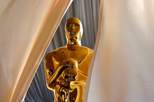 An Oscar statue is pictured at the red carpet of the 97th Annual Academy Awards, between cream drapes