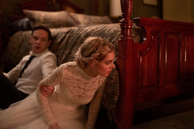 Mark O'Brien as Alex Le Domas grabs Samara Weaving's arm as Grace, dressed in a wedding gown, as they hide by the side of a bed in Ready or Not