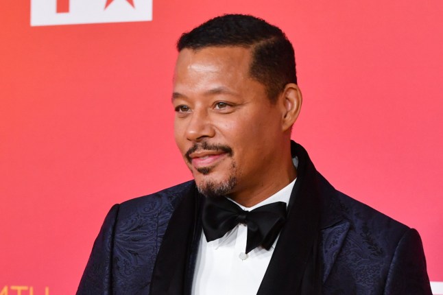 Terrance Howard poses in a navy brocade dinner jacket and blakc bowtie at the 54th Annual NAACP Image Awards. He stands against a pink backdrop