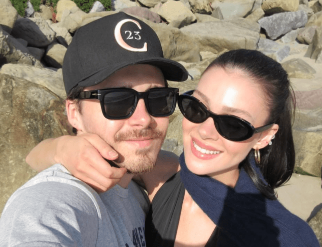 Brooklyn Beckham and Nicola Peltz Beckham smile for selfie together in the sunshine, both wearing sunglasses