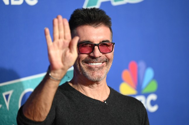 simon cowell on the red carpet in a v-neck top and orange sunglasses