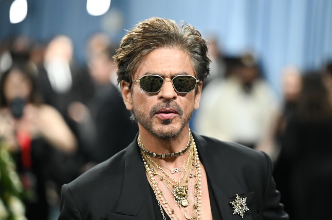 Shah Rukh Khan in sunglasses, a black jacket and strands of necklaces and a brooch at The 2025 Met Gala