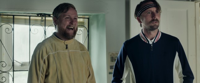 Tim McKey as Charles Heath beaming and Tom Basden as Herb McGwyer, looking confused, in old-fashioned tennis clothes in The Ballad of Wallis Island